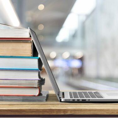 Stack of books with laptop on wooden table